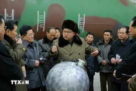Nhà lãnh đạo Triều Tiên Kim Jong-un (giữa) trong một cuộc gặp với các nhà khoa học và kỹ thuật viên trước mô hình một phần đầu đạn hạt nhân thu nhỏ ngày 9/3. (Nguồn: Yonhap/TTXVN)