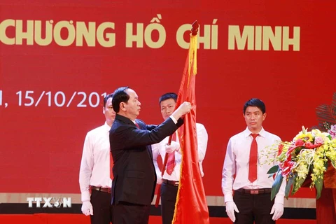 Chủ tịch nước Trần Đại Quang gắn Huân chương Hồ Chí Minh lên Cờ truyền thống của Trường Đại học Bách Khoa Hà Nội. (Ảnh: Quý Trung/TTXVN)