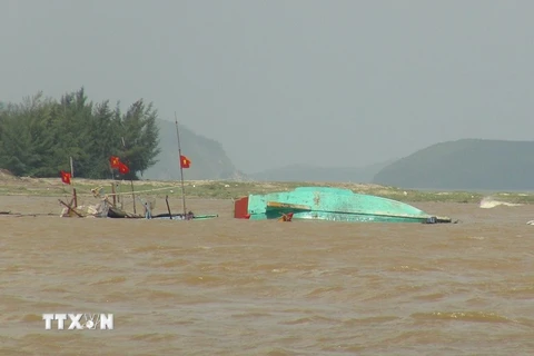 Tàu cá bị sóng đánh chìm tại cửa biển Ròon, xã Cảnh Dương, huyện Quảng Trạch, tỉnh Quảng Bình (Ảnh chụp lúc 13 giờ ngày 16/10/2016). (Ảnh: Đức Thọ/TTXVN)