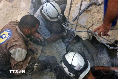 Giải cứu người bị thương mắc kẹt trong đống đổ nát sau một cuộc không kích ở quận Fardous, khu vực lân cận Aleppo ngày 11/10. (Nguồn: AFP/TTXVN)