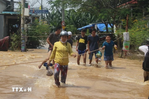 Tại xã Phước Tân (TP. Biên Hòa), chính quyền địa phương phải căng dây để người dân bám víu khi đi qua vùng ngập lụt. (Ảnh: Sỹ Tuyên/TTXVN)