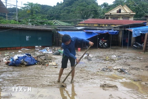 Người dân huyện Minh Hóa đang dọn dẹp nhà, cửa hàng sau khi nước rút. (Ảnh: Võ Dung/TTXVN)