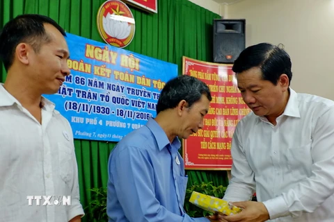 Ủy viên Bộ Chính trị, Bí thư Thành ủy Thành phố Hồ Chí Minh Đinh La Thăng tặng quà cho các gia đình chính sách khó khăn tại Khu phố 4, phường 7, quận 3. (Ảnh: Thế Anh/TTXVN)