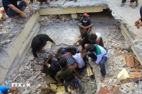 Nhân viên cứu hộ tìm kiếm nạn nhân bị mắc kẹt dưới những đống đổ nát sau trận động đất ở Pidie Jaya, tỉnh Aceh. (Nguồn: AFP/TTXVN)