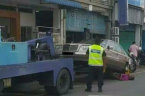 Người đàn ông nằm dưới bánh xe Mercedes để ngăn cản chiếc xe bị kéo đi. (Nguồn: Nst.com.my)