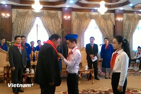 Một thiếu nhi tiêu biểu của Việt Nam đang quàng khăn đỏ cho Tổng Bí thư, Chủ tịch nước Lào Bounnhang Volachith. (Ảnh: Phạm Kiên/Vietnam+)