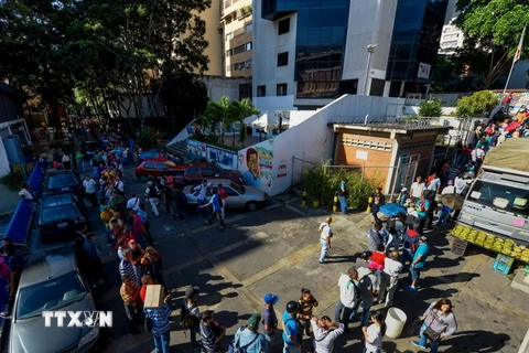 Người dân Venezuela xếp hàng chờ đổi tiền bên ngoài ngân hàng trung ương ở Caracas ngày 16/12. (Nguồn: AFP/TTXVN)