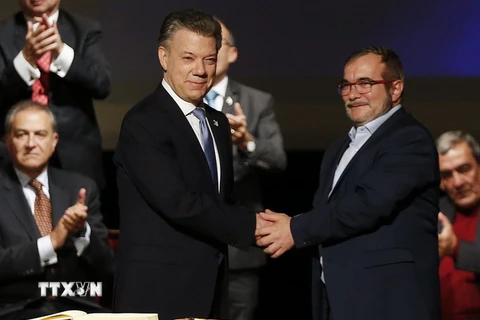 Tổng thống Colombia Juan Manuel Santos (trái, trước) và Thủ lĩnh tối cao FARC Rodrigo Londono Echeverri sau lễ ký Thỏa thuận hòa bình sửa đổi ở Bogota ngày 24/11. (Nguồn: AP/TTXVN)