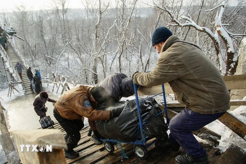 Người dân đi qua chốt kiểm soát giữa quân đội Ukraine và lực lượng đòi độc lập bằng chiếc thang gỗ thay thế cho chiếc cầu bị phá hủy trong một đợt giao tranh ở khu vực Luhansk ngày 16/12. (Nguồn: EPA/TTXVN)