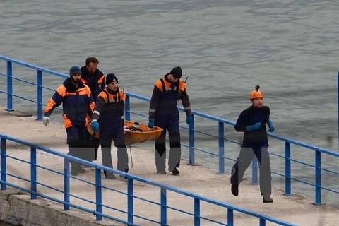Các nhân viên cứu hộ đưa thi thể nạn nhân vào bờ. (Nguồn: THX/TTXVN)
