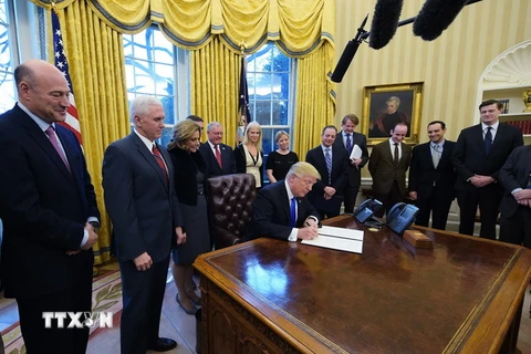 Tổng thống Mỹ Donald Trump (ngồi, trái) ký sắc lệnh hành pháp cấm tạm thời người tị nạn vào Mỹ, tại Nhà Trắng ngày 28/1. (Nguồn: AFP/TTXVN)