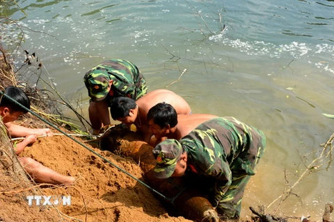 Lực lượng công binh thuộc Bộ Chỉ huy Quân sự tỉnh Phú Yên di chuyển quả bom từ bờ sông lên bờ để xử lý hủy nổ. (Ảnh: Thế Lập/TTXVN)