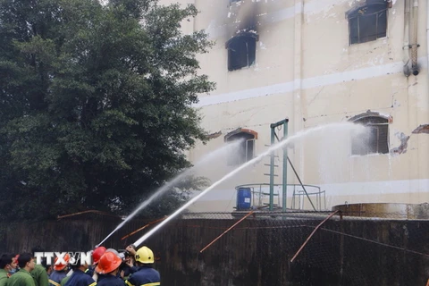 Lực lượng cứu hỏa phun nước dập tắt đám cháy trong nhà xưởng. (Ảnh: Thanh Liêm/TTXVN)