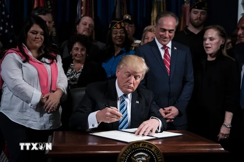  Tổng thống Mỹ Donald Trump (giữa) ký một sắc lệnh ở Washington, DC ngày 27/4. (Nguồn: AFP/TTXVN)