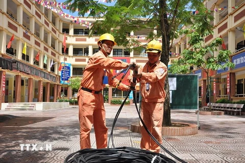 Công nhân điện lực Hà Nội kéo bổ sung nguồn dây cấp điện cho khu dân cư. (Ảnh Mạnh Khánh/TTXVN)