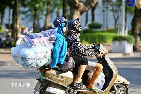 Người dân mặc áo chống nắng, bịt kín mặt khi ra đường. (Ảnh: Minh Quyết/TTXVN)