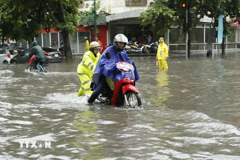 Cảnh sát giao thông Hà Nội giúp dân vượt qua chỗ ngập tại phố Lý Thường Kiệt-Phan Bội Châu. (Ảnh: Doãn Tấn/TTXVN)