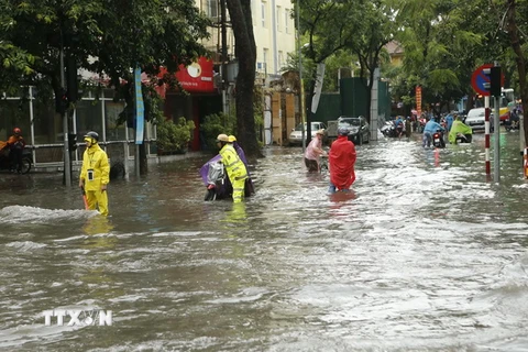 Cảnh sát giao thông Hà Nội giúp dân vượt qua chỗ ngập tại phố Lý Thường Kiệt-Phan Bộ Châu. (Ảnh: Doãn Tấn/TTXVN)