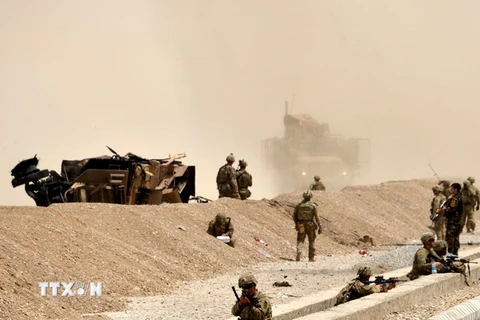 Binh sỹ Mỹ gác tại hiện trường, bên chiếc xe hộ tống bị phá hủy sau vụ tấn công ở Kandahar ngày 2/8. (Nguồn: EPA/TTXVN)