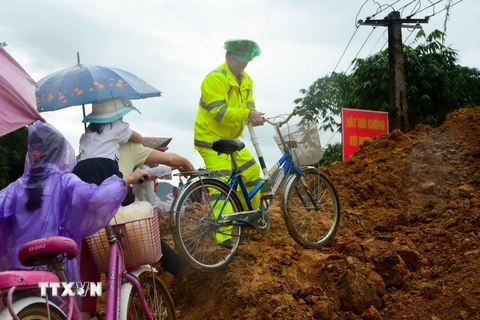 Lực lượng Cảnh sát giao thông giúp các em học sinh di chuyển qua điểm sạt lở để tới trường. (Ảnh: Xuân Tư/TTXVN)