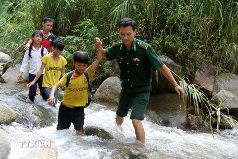 Bộ đội biên phòng giúp học sinh các bản thuộc xã Pa Vệ Su vượt suối đến trường đúng ngày khai giảng năm học mới. (Ảnh: Nguyễn Hoàng/TTXVN)