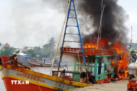 Lực lượng Biên phòng Sóc Trăng cùng nhân dân tham gia chữa cháy tàu cá của ngư dân. (Ảnh: Trung Hiếu/TTXVN)