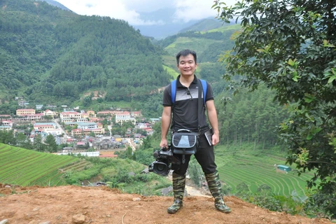Nhà báo Đinh Hữu Dư trên đường tác nghiệp (Ảnh: Nội san TTXVN)