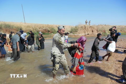 Binh sĩ quân đội Iraq giúp đỡ người dân qua sông gần thành phố Kirkuk ngày 4/10. (Nguồn: THX/TTXVN)