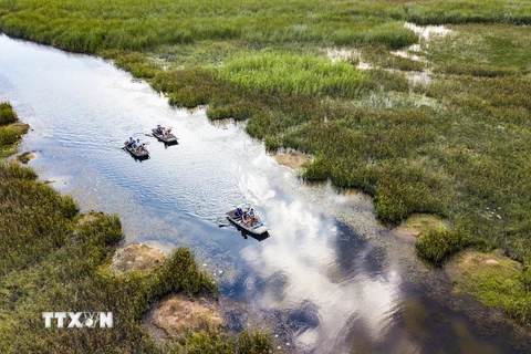 Du khách đi thuyền tham quan Khu bảo tồn thiên nhiên Vân Long. (Ảnh: Minh Đức/TTXVN)