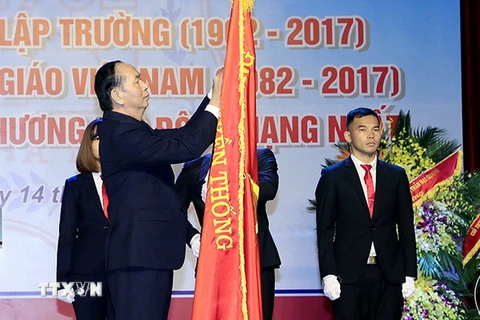 Chủ tịch nước Trần Đại Quang gắn Huân chương Lao động hạng Nhất lên lá cờ truyền thống của Trường Đại học Y Hà Nội. (Ảnh: Nhan Sáng/TTXVN)