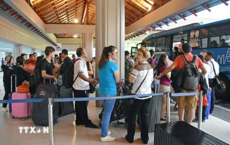 Hành khách đợi xe buýt tại sân bay Bali ngày 28/11. (Nguồn: Kyodo/TTXVN)