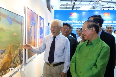 Ông Trần Khánh Chương, Chủ tịch Hội Mỹ thuật Việt Nam (áo trắng) giới thiệu tranh với Bộ trưởng Thông tin-Văn hóa và Du lịch Lào, ông Bosengkham Vongdala. (Ảnh: Phạm Kiên/TTXVN)