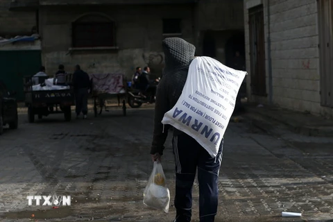 Người dân Palestine chuyển lương thực cứu trợ bên ngoài trung tâm phân phối lương thực của LHQ tại Gaza ngày 15/1. (Nguồn: AFP/TTXVN)