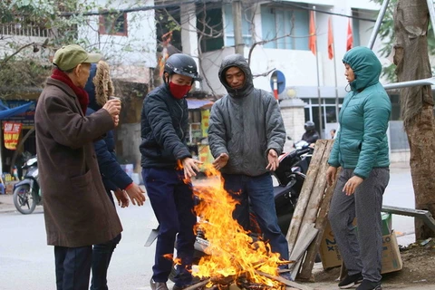 Người dân tại Hà Nội đốt củi để sưởi ấm tránh rét. (Ảnh: Quang Quyết/TTXVN)