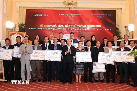 Thủ tướng Nguyễn Xuân Phúc trao tặng tiền số tiền cho 20 huyện nghèo qua đấu giá trái bóng và áo Đội tuyển U23 Việt Nam. (Ảnh: Thống Nhất/TTXVN)