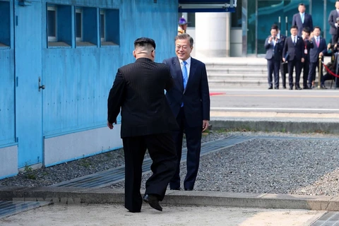 Tổng thống Hàn Quốc Moon Jae-in đón Nhà lãnh đạo Triều Tiên Kim Jong-un (trái) tại đường phân định ranh giới hai miền ở làng đình chiến Panmunjom. (Nguồn: YONHAP/TTXVN)