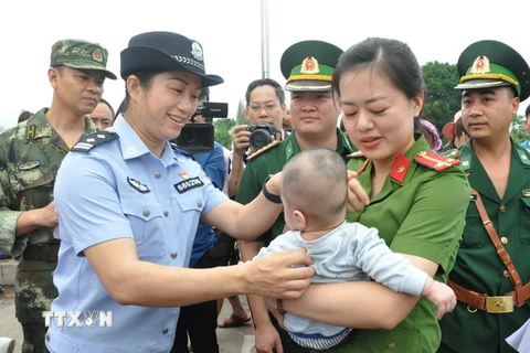 Lực lượng chức năng Việt Nam tiếp nhận em bé bị bán sang Trung Quốc. (Ảnh:Nguyễn Hoàng/TTXVN)