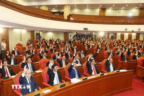 Các đồng chí lãnh đạo Đảng, Nhà nước và các đại biểu biểu quyết thông qua Nghị quyết Hội nghị lần thứ bảy. (Ảnh: Trí Dũng/TTXVN)