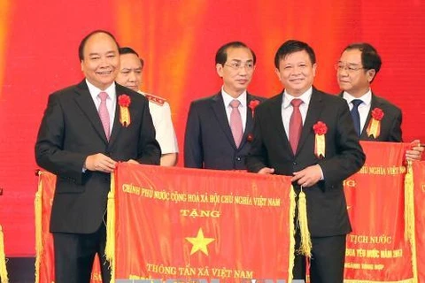 Thủ tướng Nguyễn Xuân Phúc tặng cờ thi đua của Chính phủ cho Thông tấn xã Việt Nam, đơn vị dẫn đầu phong trào thi đua yêu nước năm 2017. (Ảnh: Doãn Tấn/TTXVN)