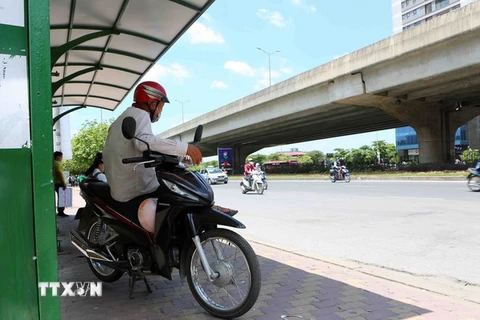 Người hành nghề xe ôm tránh nắng ở bến xe buýt trên tuyến đường Phạm Hùng. (Ảnh: Thành Đạt/TTXVN)