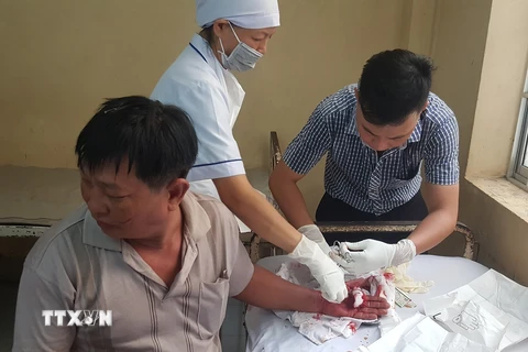 Nhân viên Bệnh viện Đa khoa Bạc Liêu khâu vét thương cho nạn nhân bị thương. (Ảnh: Huỳnh Sử/TTXVN)