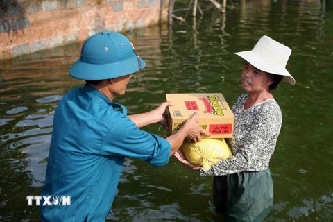Quà hỗ trợ của Hội Chữ thập Đỏ thành phố Hà Nội được giao tận tay người dân trong vùng ngập. (Ảnh: Thanh Tùng/TTXVN)