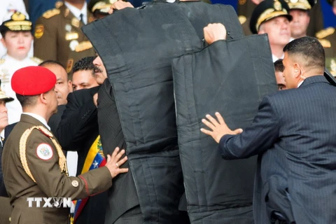  Lực lượng an ninh bảo vệ Tổng thống Venezuela Nicolas Maduro sơ tán khỏi hiện trường vụ nổ nhằm vào lễ kỷ niệm 81 năm ngày thành lập lực lượng Phòng vệ Quốc gia Venezuela ở Caracas ngày 4/8. (Ảnh: THX/ TTXVN)
