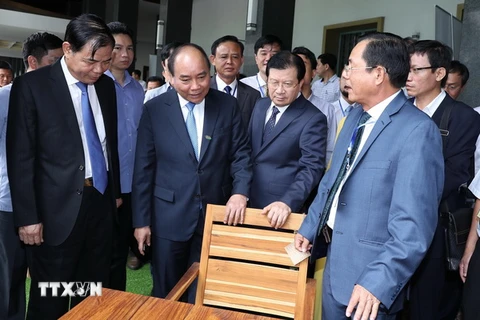 Thủ tướng Nguyễn Xuân Phúc và các đại biểu tham quan các sản phẩm đồ gỗ trưng bày tại hội nghị. (Ảnh: Thống Nhất/TTXVN)