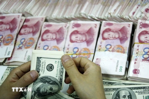 Đồng tiền giấy 100 USD (trên) và đồng 100 Nhân dân tệ (phía dưới) tại một ngân hàng ở Hoài Bắc, tỉnh An Huy, Trung Quốc. (Nguồn: AFP/ TTXVN)