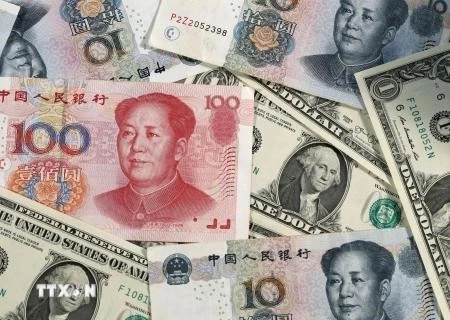 Đồng Nhân dân tệ (phía trên) của Trung Quốc và đồng USD. (Ảnh: Kyodo/TTXVN)