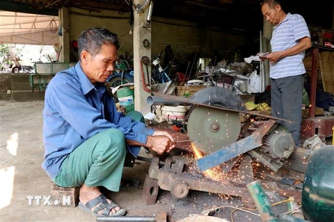 Ông Nguyễn Văn Hoàn với công việc chế tạo, cải tiến máy móc phục vụ sản xuất nông nghiệp. (Ảnh: Quang Cường/TTXVN)