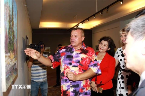 Họa sĩ Mikhail Vyacheslavovich Stoyachko giới thiệu với các đại biểu về tranh "Phong cảnh nước Nga" tại triển lãm. (Ảnh: Thanh Vũ/TTXVN)