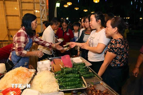 Người dân tham quan và mua món ăn tại các gian hàng ẩm thực. (Ảnh: Thành Đạt/TTXVN)