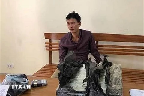 Đối tượng Nguyễn Ngọc Ích cùng tang vật 30 bánh heroin tại cơ quan điều tra. (Ảnh: TTXVN phát)